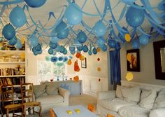 a living room filled with lots of furniture and balloons hanging from the ceiling above it