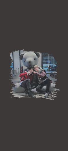 two people are posing in front of a giant teddy bear with their arms around each other