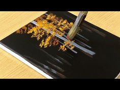 a pen is sitting on top of a book with yellow trees in the pages and black cover