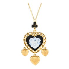 This breathtaking Dolce and Gabbana necklace is an elevated piece that exudes old world elegance. The 18K Yellow Gold heart-shaped pendant which measures 1.75 long by 1.0 wide comes to life thanks to ornate metalwork, floral motifs, Black Jade accents, and a trio of inset Sapphire gemstones. Its suspended from a 20 chain with lobster clasp closure.This jewelry piece is offered in estate condition and includes a gift box. Ornate Metalwork, Trinity Necklace, Old World Elegance, Diamond Drop Pendant, Dolce And Gabbana Handbags, White Gold Pendant Necklace, Black Jade, Contemporary Pendant, Jade Necklace