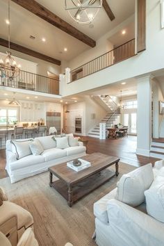 a living room filled with white couches and a coffee table in front of a staircase