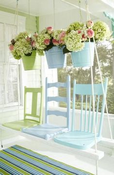 two chairs with flower pots on them sitting in front of a window, one is blue and the other is green