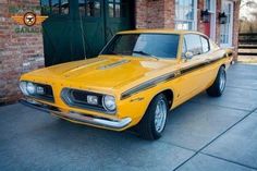 an old yellow car parked in front of a brick building