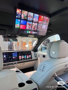 the interior of a car with several large screens on the wall above it's headrests