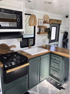 a kitchen with green cabinets and black appliances in the back wall, along with a wooden counter top