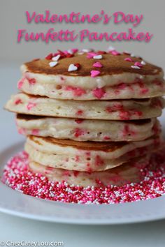 a stack of pancakes with pink sprinkles on a white plate, ready to be eaten