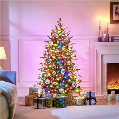 a brightly lit christmas tree in a living room with presents on the floor next to it