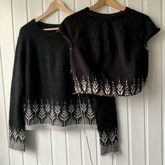 two sweaters hanging up against a white wall