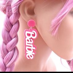 a pair of pink earrings with the word barbie on it