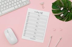 a pink desk with a keyboard, mouse and planner