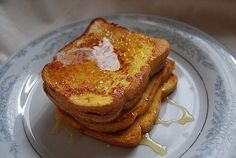 three pieces of french toast sitting on top of a blue and white plate with syrup drizzled all over it