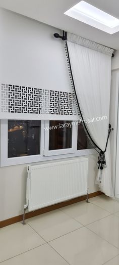 an empty room with a white curtain and window in the corner, next to a radiator