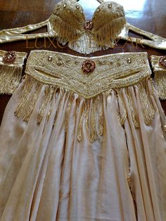 a dress with gold fringes on it sitting on a table