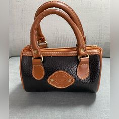 This Is An Adorable Mini Barrel Bag. It Is Vegan Leather That Looks Like Genuine Pebble Leather. It Is In Mint Condition. It Is New Without Tags. No Callouts At All Inside Or Out. The Body Is Imperfect Condition. It Is Black With Brown Trim And Brown Hinged Handles. They Are On Silver Metal Hinges. The Front Of The Bag Has A Brown Patch That Says “Genuine Classic Original“. There Are Cream Stitches That Adore The Bag. The Inside Of The Bag Is Lined With A Wipeable Black Fabric. 6”Wx6”Tx3”D Small Vintage Bag For Everyday Use, Small Brown Bags For Everyday Use, Brown Rectangular Portable Coin Purse, Small Brown Bag For Gift, Small Brown Gift Bag, Vintage Brown Bags, Barrel Bag, Metal Hinges, Brown Trim