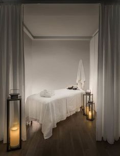 a white bed sitting next to two candles on top of a wooden floor