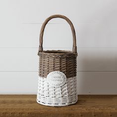 a white and brown basket sitting on top of a wooden table next to a wall