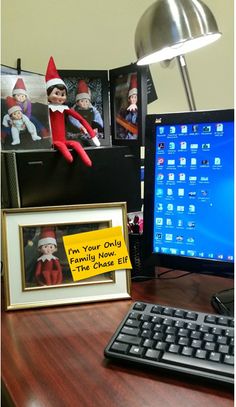 an elf's office desk with a computer, keyboard and pictures on the wall