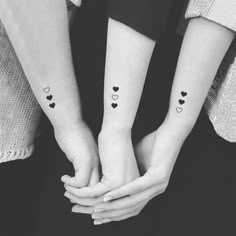 two people with matching tattoos on their arms holding each other's hands and one is holding