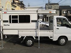 a white truck parked in front of a building with a camper attached to the back