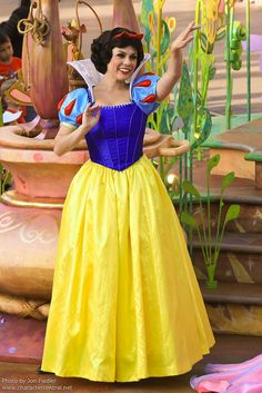 a woman dressed as snow white standing in front of a flower pot with her arms out