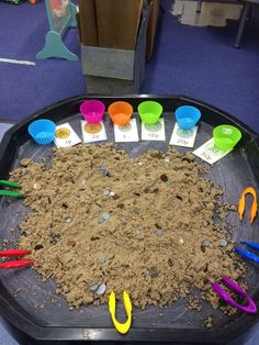 a tray filled with sand and scissors on top of a table