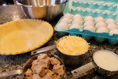 eggs, cheese and other ingredients are on the counter next to an uncooked pie