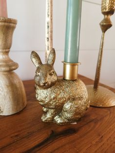 a gold rabbit figurine sitting on top of a wooden table next to candles