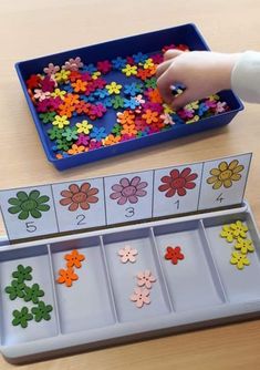 a child's hand is picking up the missing pieces from a flower themed puzzle