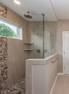 a bathroom with a walk in shower next to a white door and window on the wall