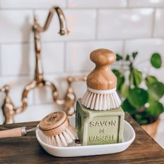 a wooden brush sitting on top of a white plate next to a soap dispenser