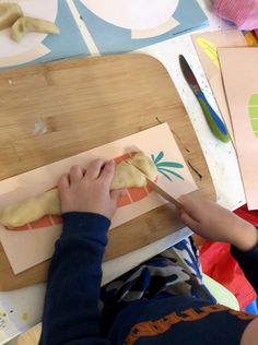 a child is making food on a cutting board with scissors and other crafting supplies