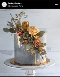 an image of a cake with flowers on the top and gold leaf decorating it