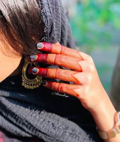 a woman with her hands on her face wearing rings and scarves, looking at the camera