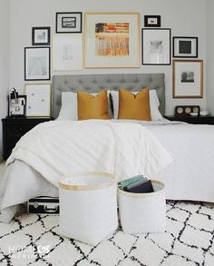 a bedroom with white bedding and pictures on the wall