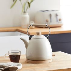 a white tea kettle sitting on top of a wooden table