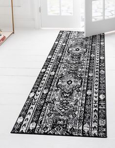 a black and white rug on the floor in front of a door with an open window