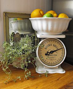 an old fashioned kitchen scale with lemons and oranges in it sitting on a table