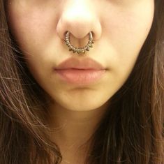 a close up of a woman with a nose ring on her nose and an object in the middle of her nose