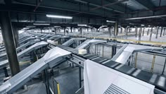 an empty warehouse filled with metal conveyor belt and doors to the top floor are open