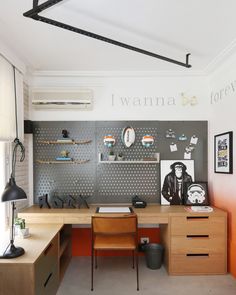 a home office with two desks and a wall mounted metal pegboard on the wall