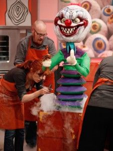 two people in aprons and an evil clown statue