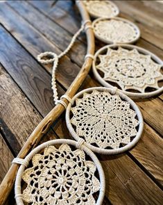 three woven doily hangings on a wooden floor with rope and wood sticks in the background