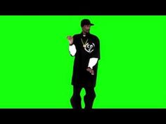 a man in a black shirt and hat is dancing on a green screen with his hands together