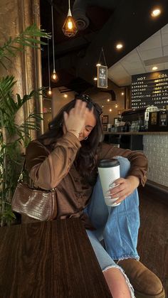 a woman sitting at a table holding a coffee cup