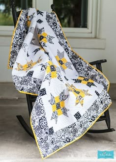 a black rocking chair with a yellow and white quilt on it