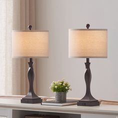 two lamps sitting on top of a table next to a book