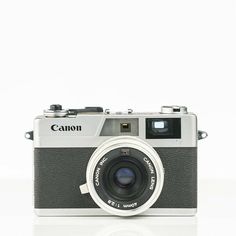 an old fashioned camera sitting on top of a white surface with the lens pointed up