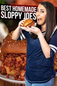 a woman holding a sandwich in front of a pile of sloppy joes