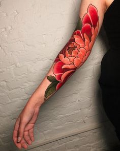 a woman's arm with a red flower tattoo on the left forearm and hand