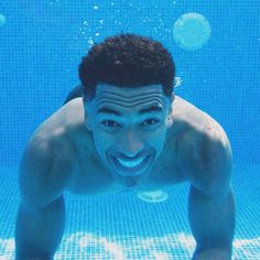 a young man swimming underwater in a pool